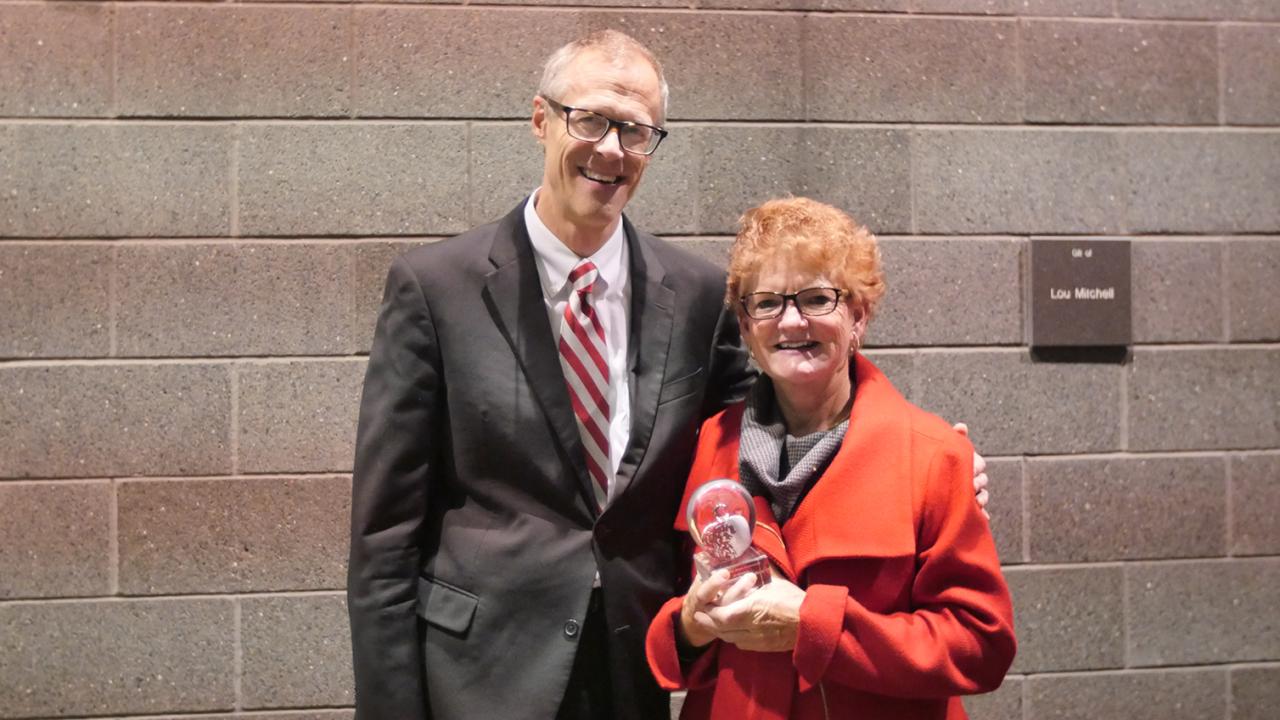 Judge Luanna Cooperrider stands next to Dean/Director William MacDonald holding the Distinguished Alumni Award glass trophy.