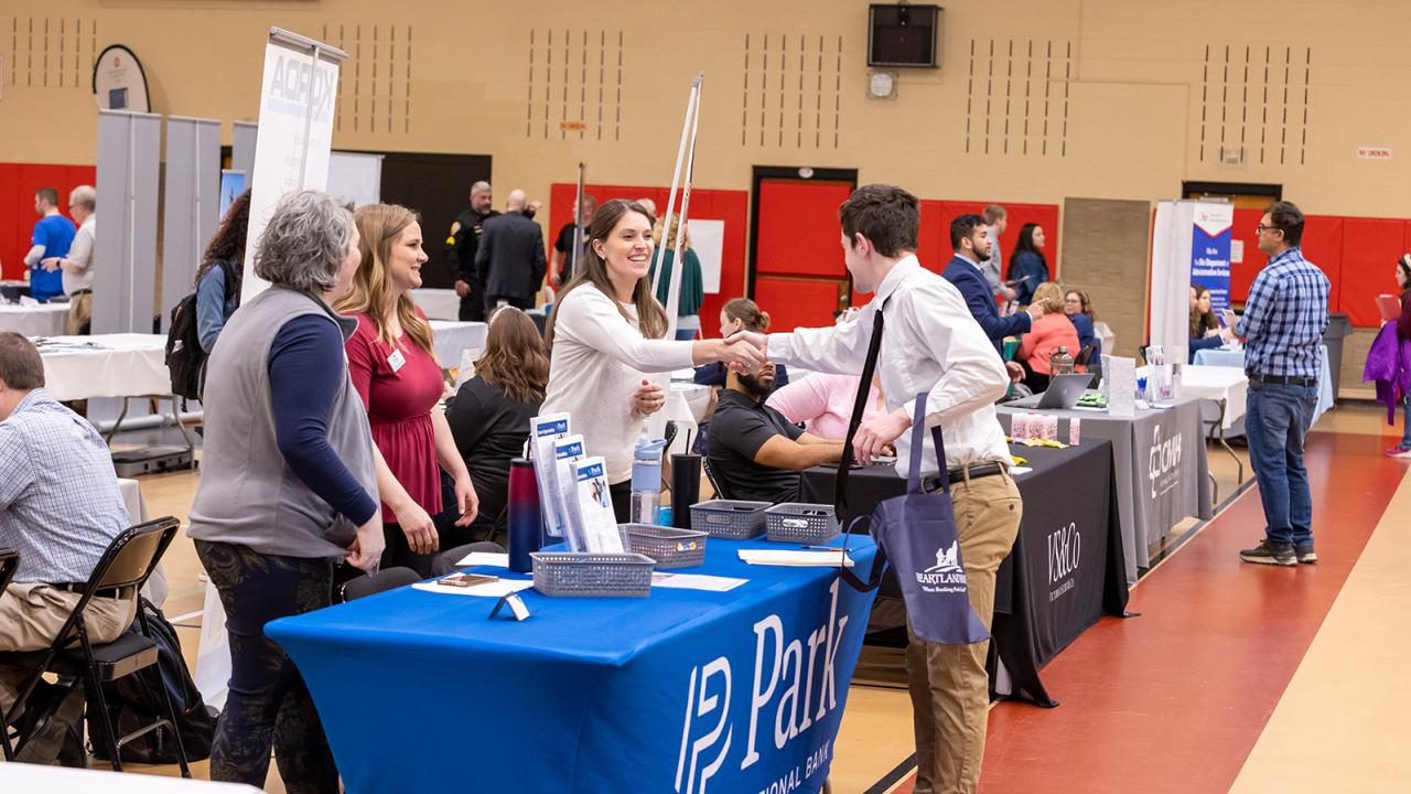 An employer shakes hands with a student at the career fair.