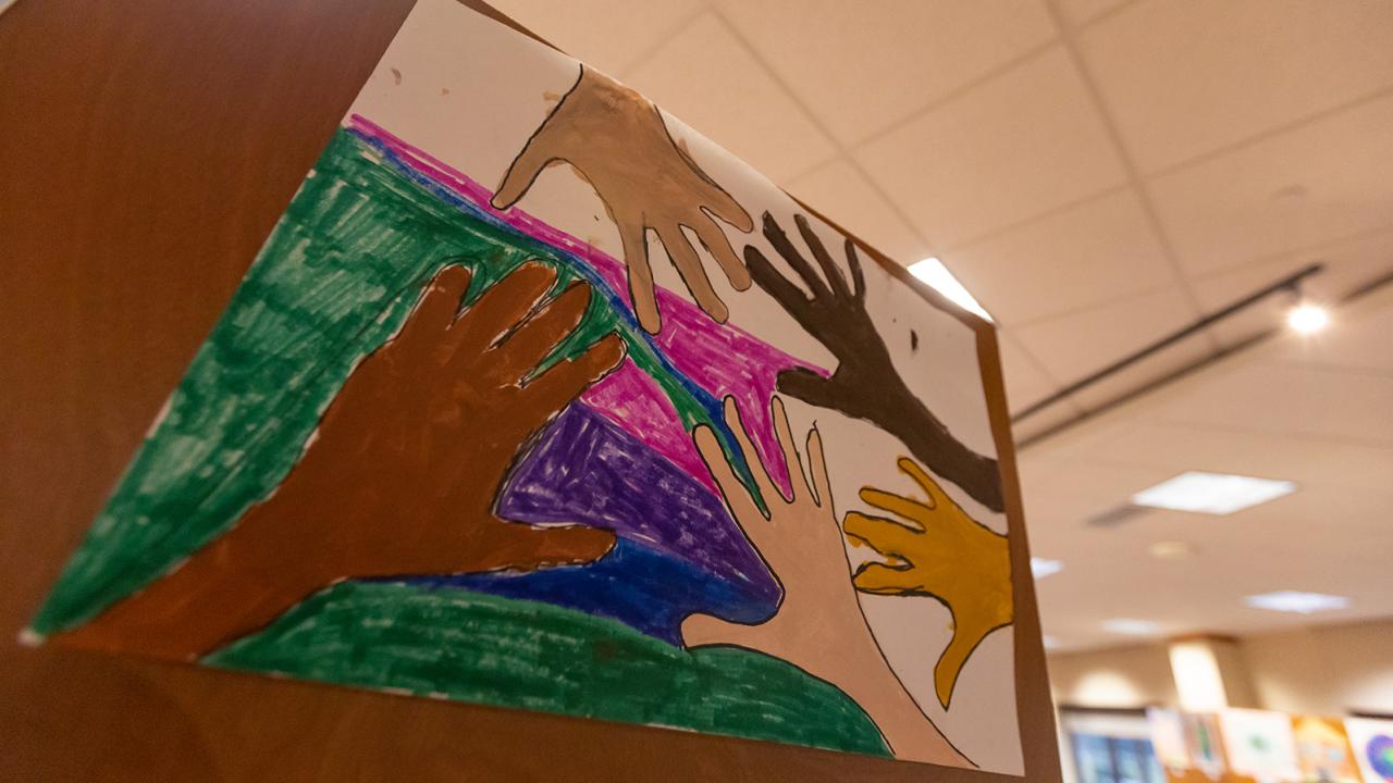 A painting of four hands of different skin tones.