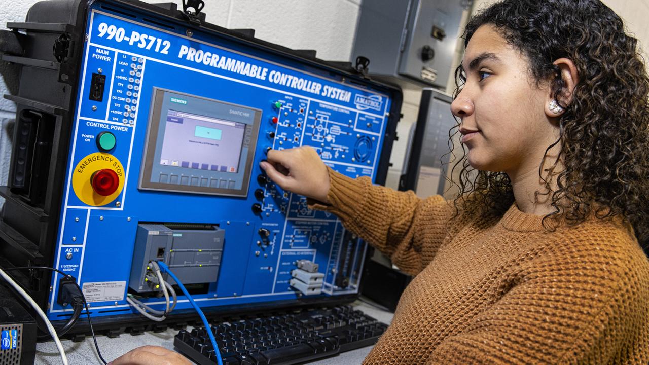 Marina uses an engineering machine in the engineering lab on campus.
