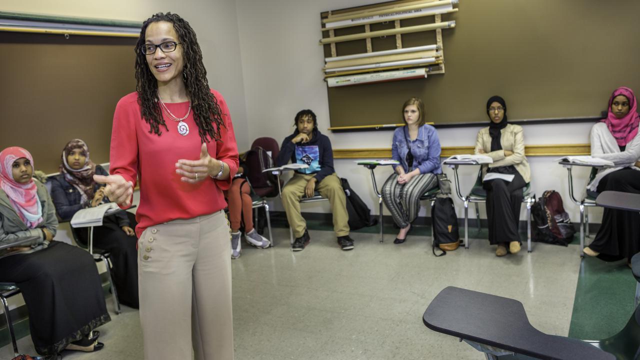 Associate Professor stands amid a semi-circle of students while teaching class.