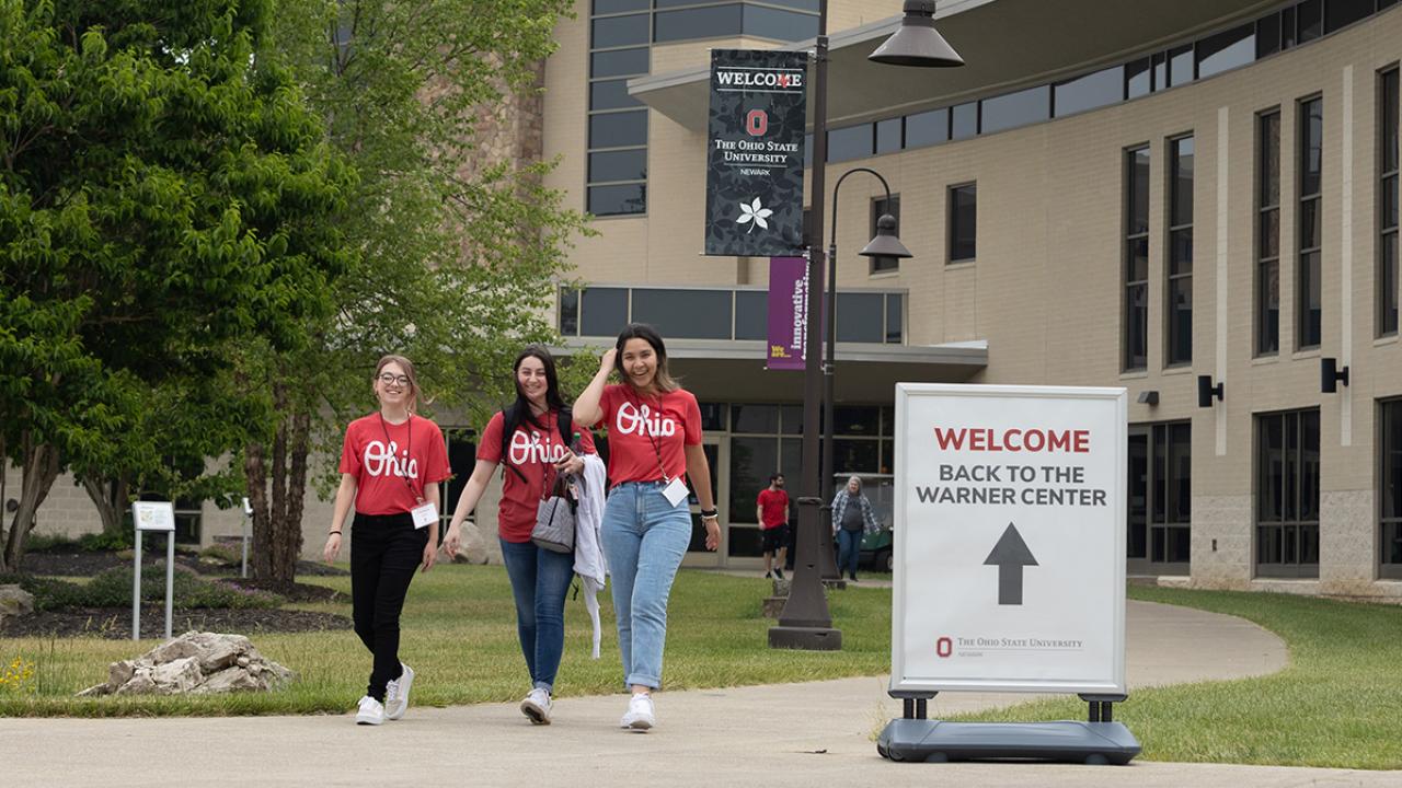 Three student tour guides by the Warner Center during orientation. 