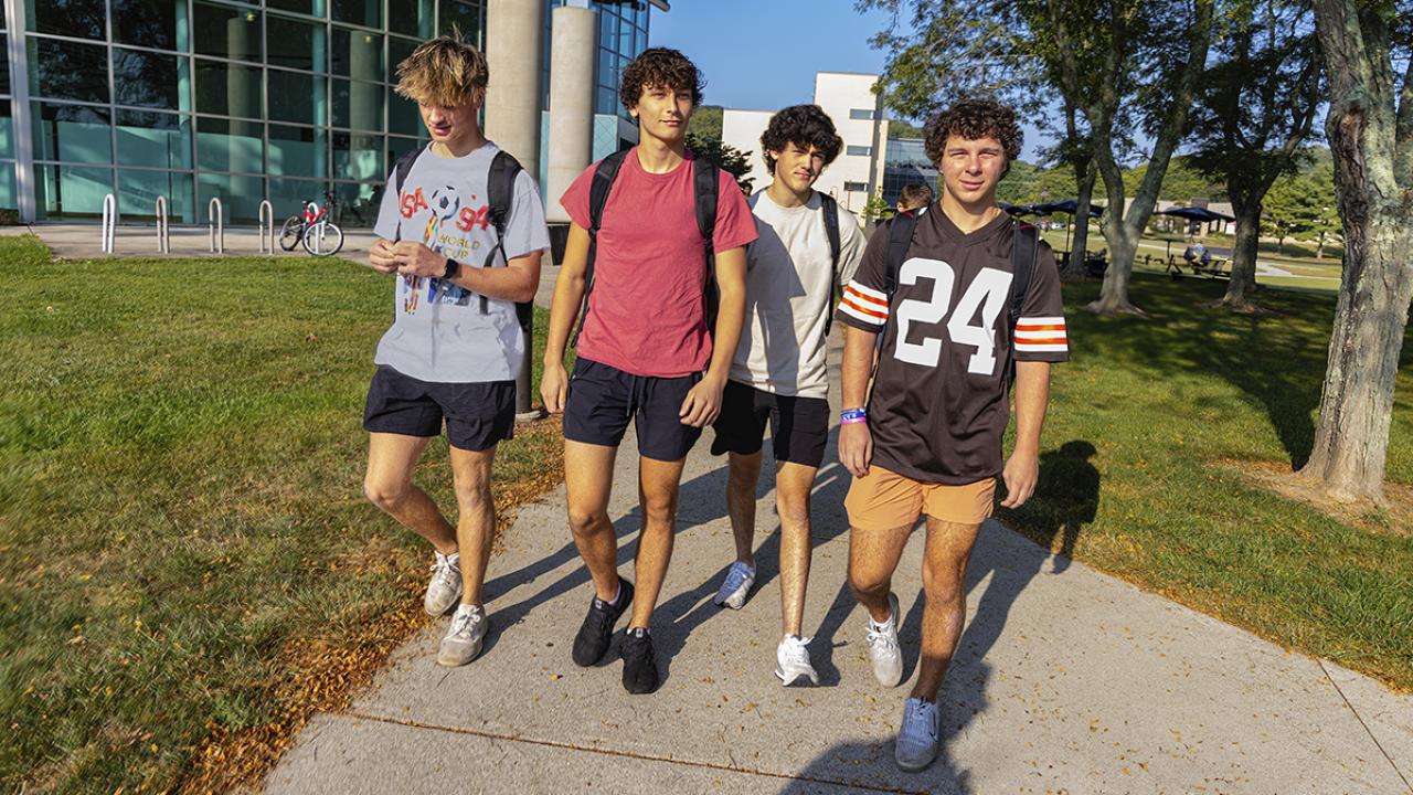 Four male students walk side-by-side outside of LeFevre Hall on campus.