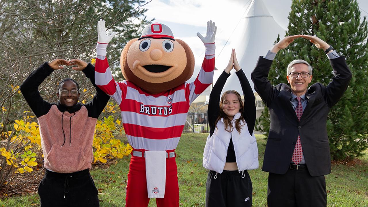 Dean Matt Smith, Brutus Buckeye and two students form the letters O, H, I, O with their hands.