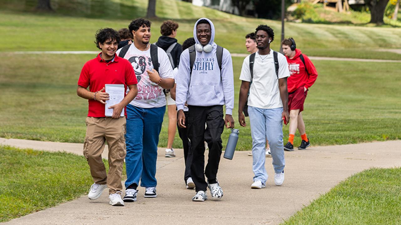 A group of students walks on the sidewalk on the first day of autumn semester.